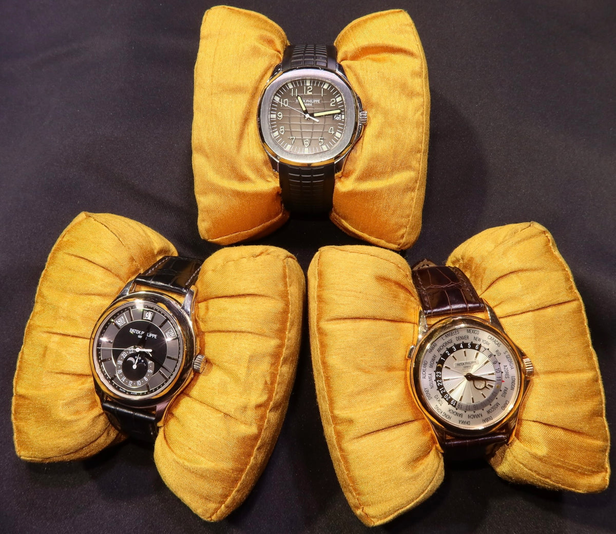 Explore luxury wristwatches: three watches with leather straps on gold cushions.