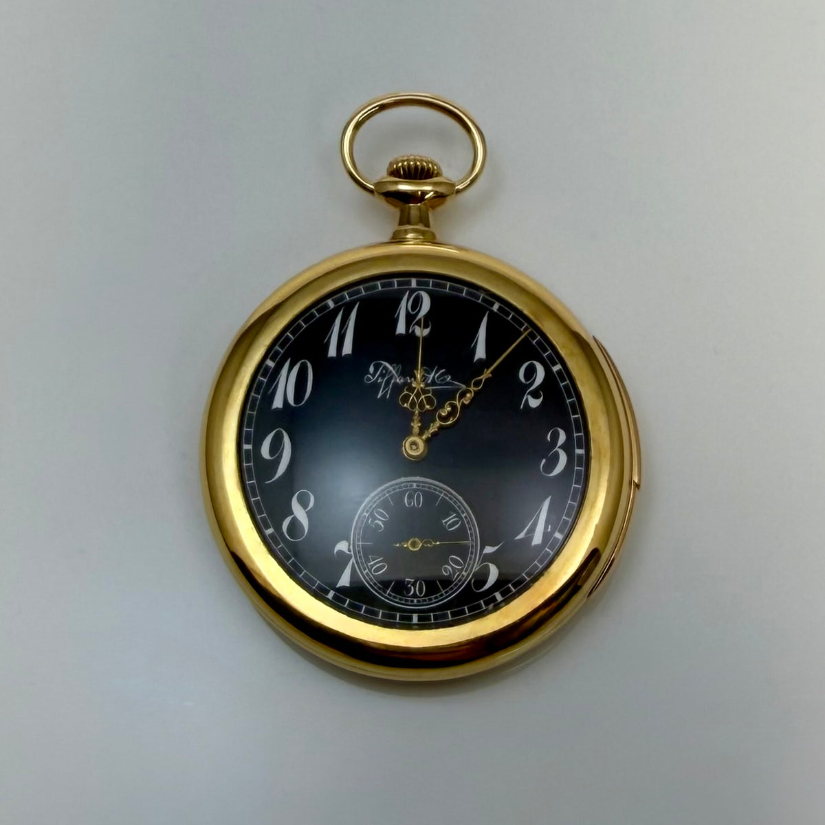 Pocket watch with a black dial, ornate gold-tone hands, and a small seconds subdial.